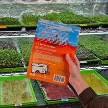 Cargar imagen en el visor de la galería, Person holding Becoming a Microgreen Master with on the grow book with microgreens in the background