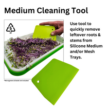 Load image into Gallery viewer, Green scraper tool being used to remove microgreen roots and stems from a reusable silicone grow medium in a large sprouting tray