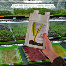 Load image into Gallery viewer, Ocean Solution 2-0-3 organic liquid fertilizer held in front of microgreens growing on a grow rack, trays sold separately