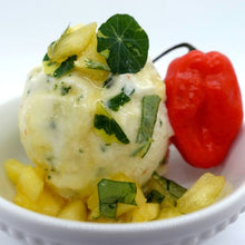 Load image into Gallery viewer, A scoop of creamy pineapple sorbet flecked with green herbs, topped with diced pineapple and a nasturtium leaf, sits in a white bowl. A single red chili pepper rests on the side, adding a pop of color.