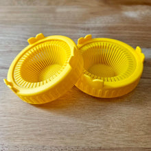 Load image into Gallery viewer, Two yellow sprouting jar lids for wide mouth mason jars shown on a wood surface