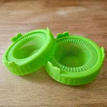 Load image into Gallery viewer, Two green sprouting jar lids for wide mouth mason jars shown on a wood surface
